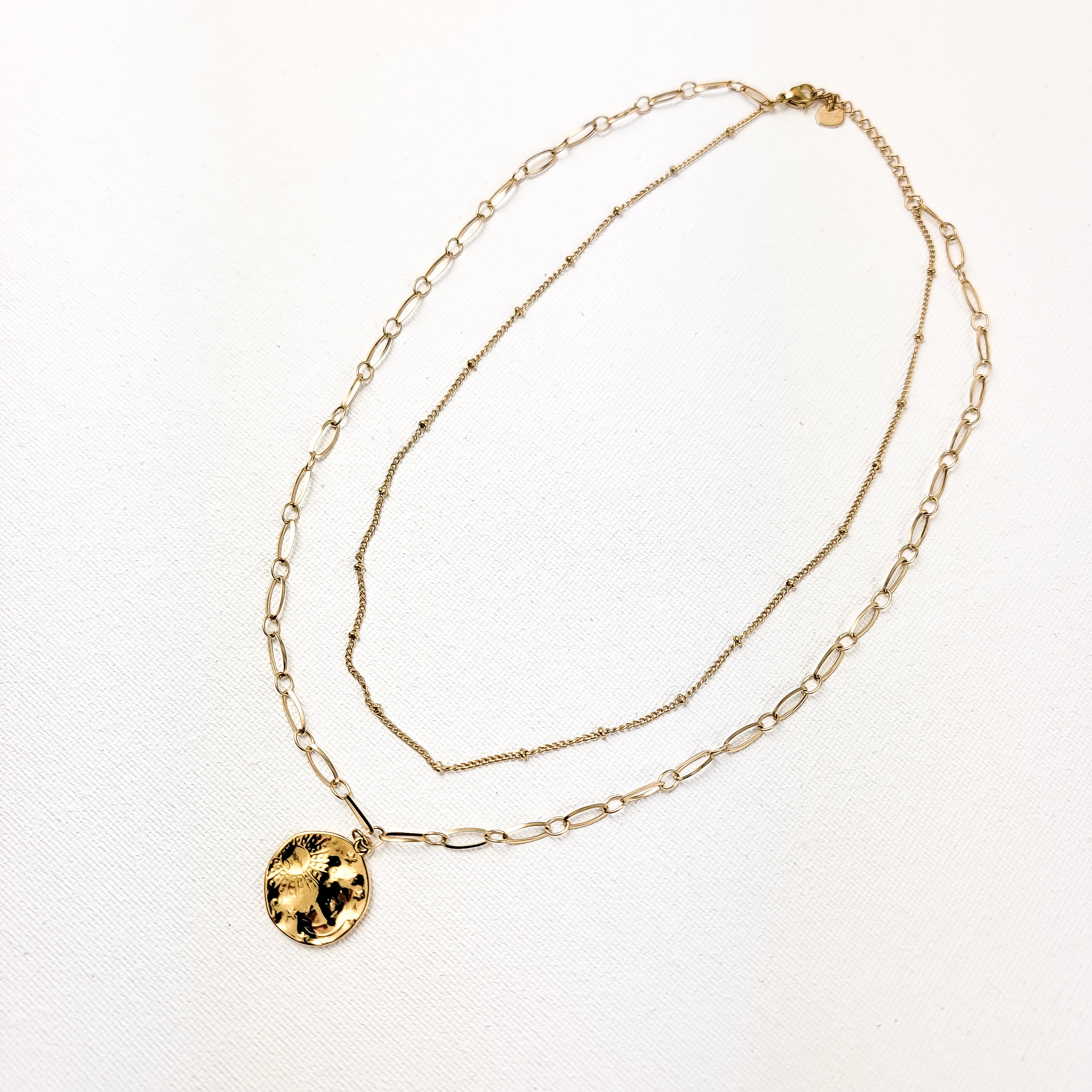 Our celestial-inspired necklace set features two intricately crafted pieces adorned with a beautifully engraved scene of the moon, stars, and sun. Crafted from stainless steel and plated in 18k gold, these necklaces offer a modern look perfect for layering this year. Embrace celestial charm with these versatile piece or layer together with more necklaces for a truly bold statement.