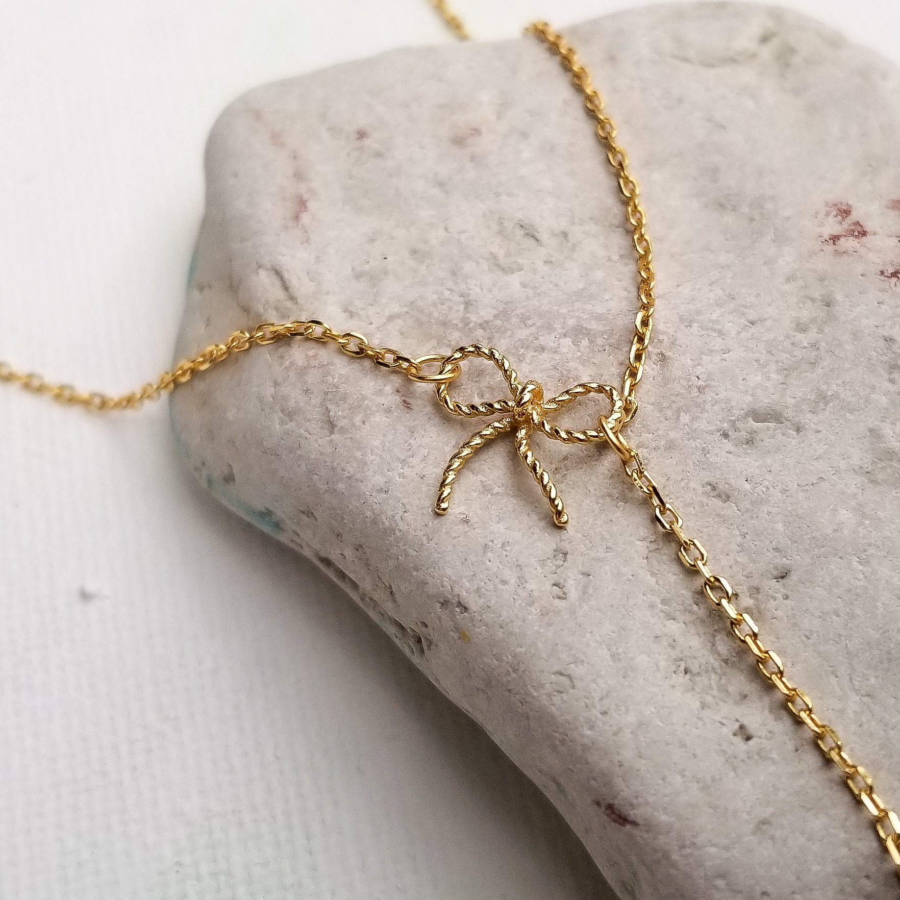 This beautiful choker - lariat style necklace features an elegant bow and a tear cut red zirconia stone. The details really stand out on this necklace. The slender chain and delicate profile make it the ideal everyday piece and it can also be a centerpiece for a special occasion. Material:  14K Gold Plated over 925 Sterling Silver Stone: Red Cubic Zirconia Style: Choker Style Necklace - Bowknot, Tassel Chain Length: 16 Inch Nickel & Lead free & Hypoallergenic
